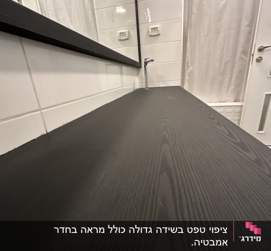 משטח עץ כהה בחדר אמבטיה עם מראה וברז